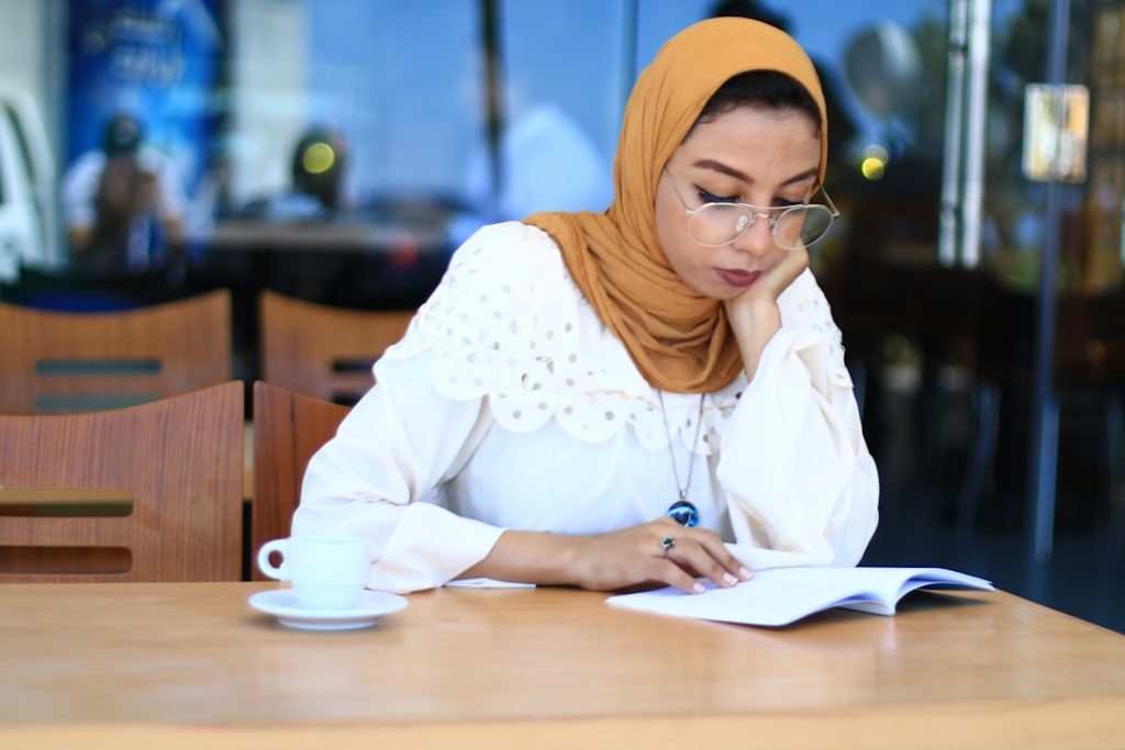 Hijabi Muslim woman carefully reviewing documents and notes, representing biodata preparation for rishta