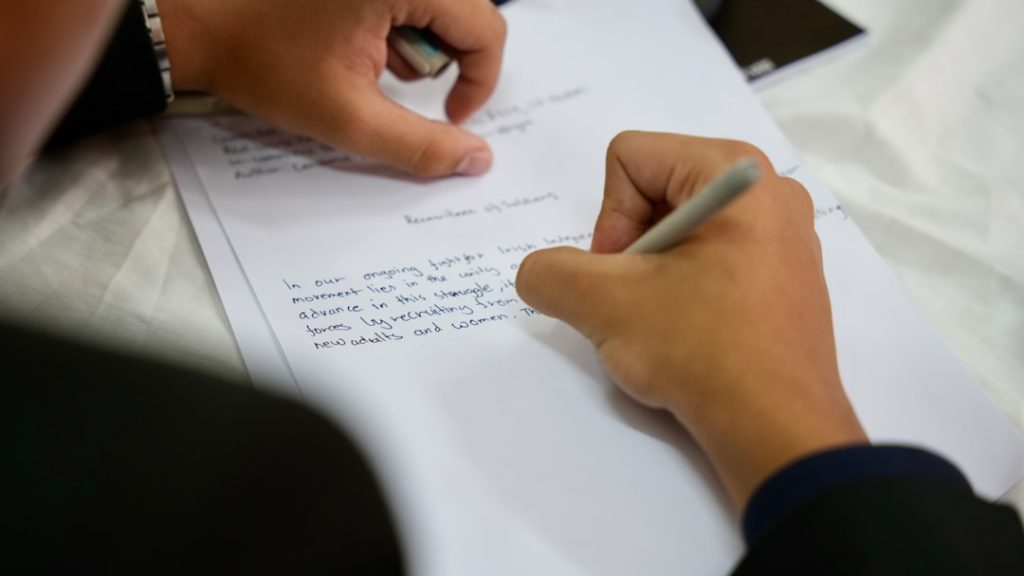 Person carefully writing a document by hand, representing the process of preparing a rishta biodata proposal