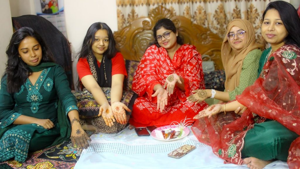 South Asian women in traditional dress displaying henna designs, representing a matrimonial celebration